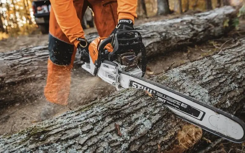 Άνδρας με φόρμα STIHL κόβει δέντρο με αλυσοπρίονο – Κατηγορία Πριόνισμα & Κοπή